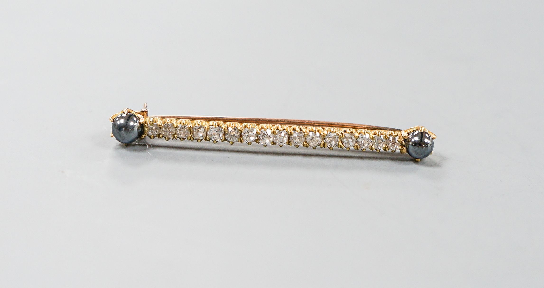 A yellow metal, two stone hematite and sixteen old cut diamond set bar brooch, 52mm, gross weight 5 grams.